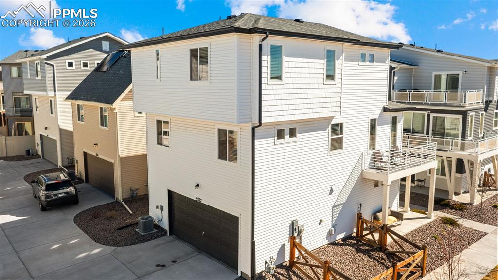 Image 33 of 37: Back of property with an attached garage, a balcony, driveway, and a patio 