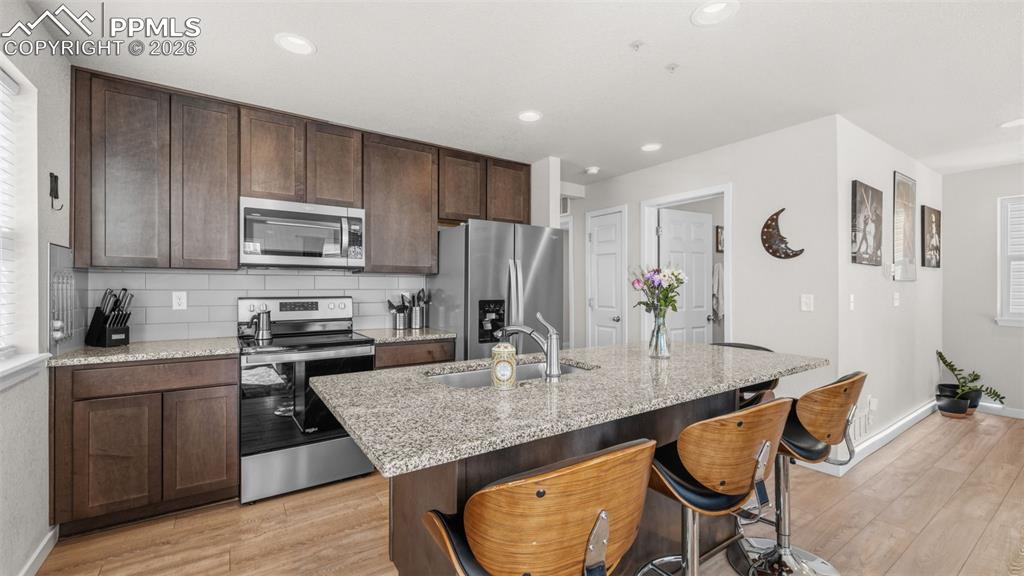 Image 7 of 37: Kitchen with stainless steel appliances, dark wood finish cabinetry, light 