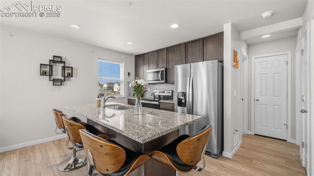 Image 8 of 37: Kitchen with dark wood finish cabinetry, stainless steel appliances, a brea