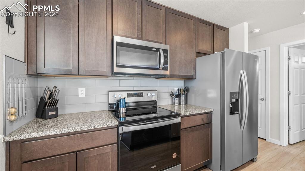 Image 9 of 37: Kitchen featuring stainless steel appliances, light stone countertops, back