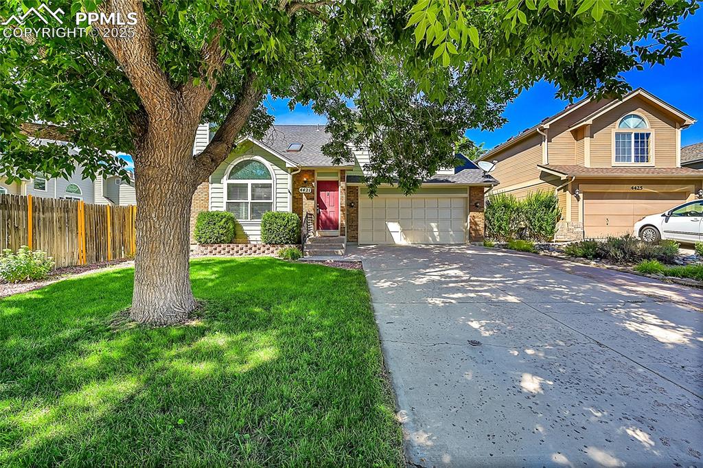 Caption: View of front facade with concrete driveway, an attached garage, and a shingled roof