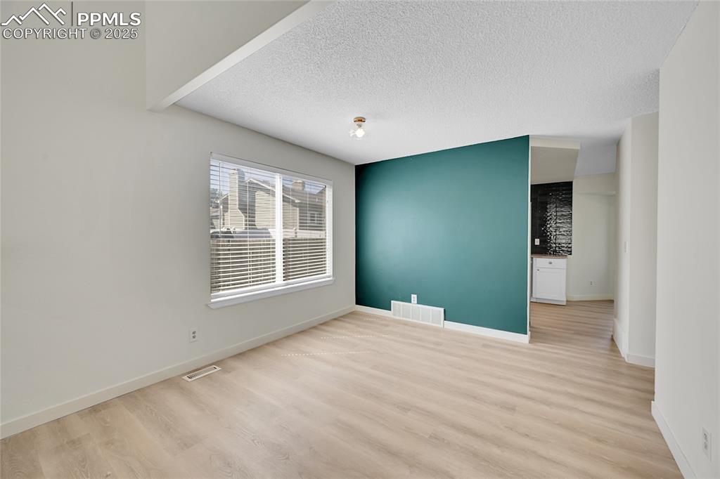 Image 10 of 39: Empty room with light wood-style flooring and a textured ceiling