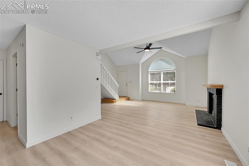 Image 12 of 39: Unfurnished living room featuring light wood-style flooring, vaulted ceilin