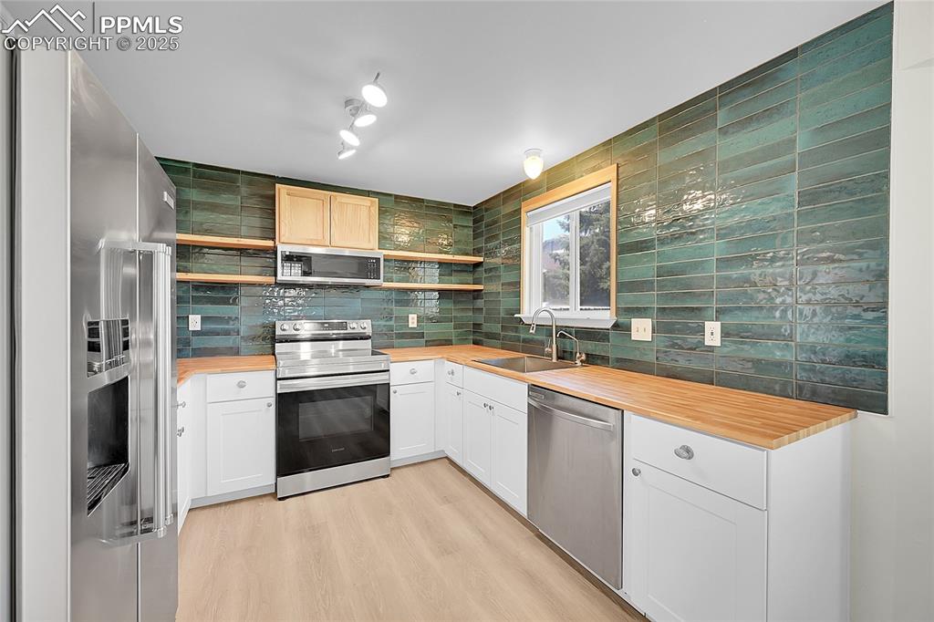 Image 13 of 39: Kitchen featuring appliances with stainless steel finishes, decorative back