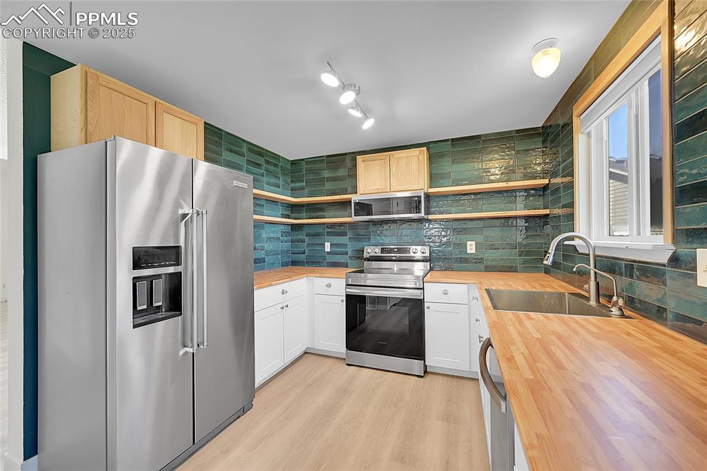 Image 14 of 39: Kitchen featuring appliances with stainless steel finishes, open shelves, b