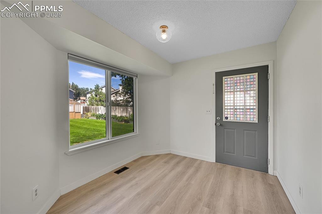 Image 16 of 39: Foyer with light wood finished floors and a textured ceiling