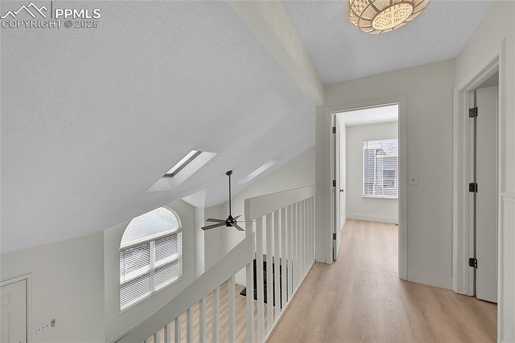 Image 20 of 39: Hall featuring a textured ceiling, lofted ceiling, a skylight, and light wo