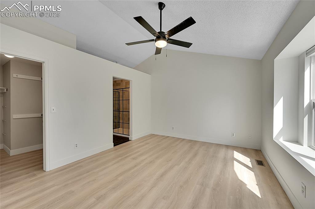 Image 22 of 39: Unfurnished bedroom with light wood-style flooring, lofted ceiling, a walk 