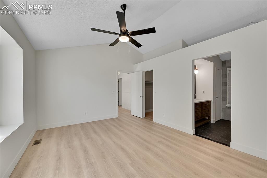 Image 23 of 39: Unfurnished bedroom featuring a walk in closet, vaulted ceiling, light wood
