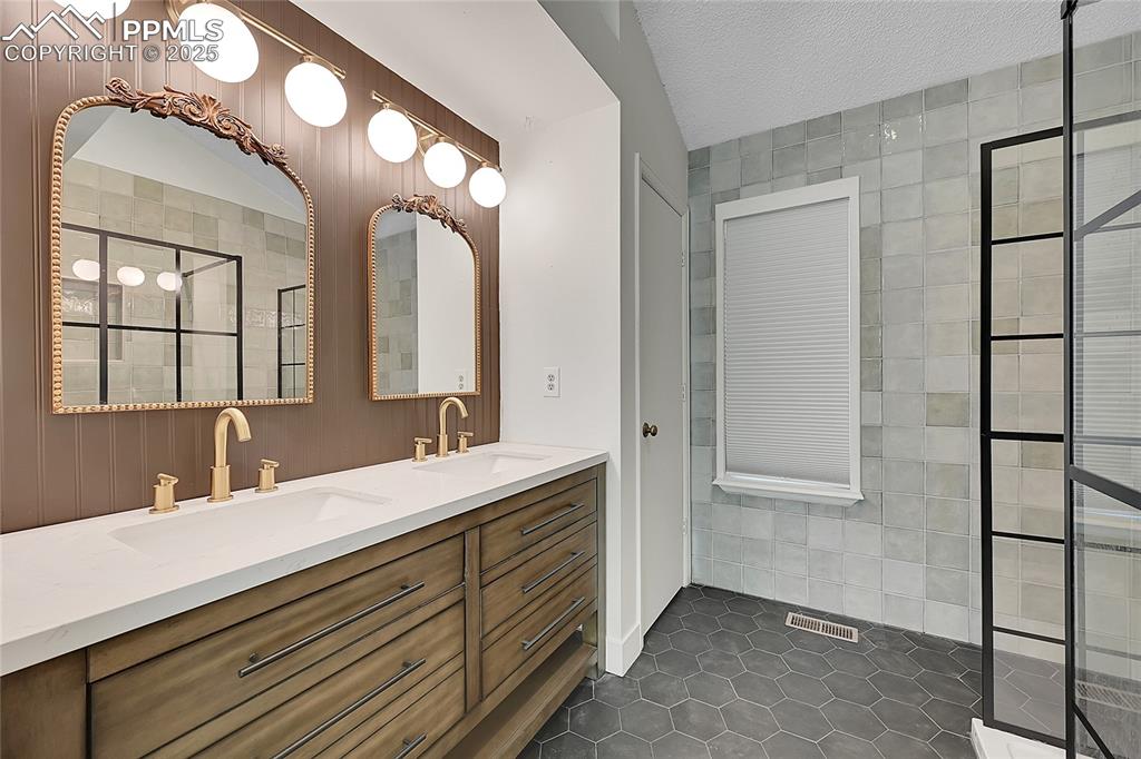 Image 24 of 39: Bathroom with dark tile patterned flooring, a stall shower, a textured ceil