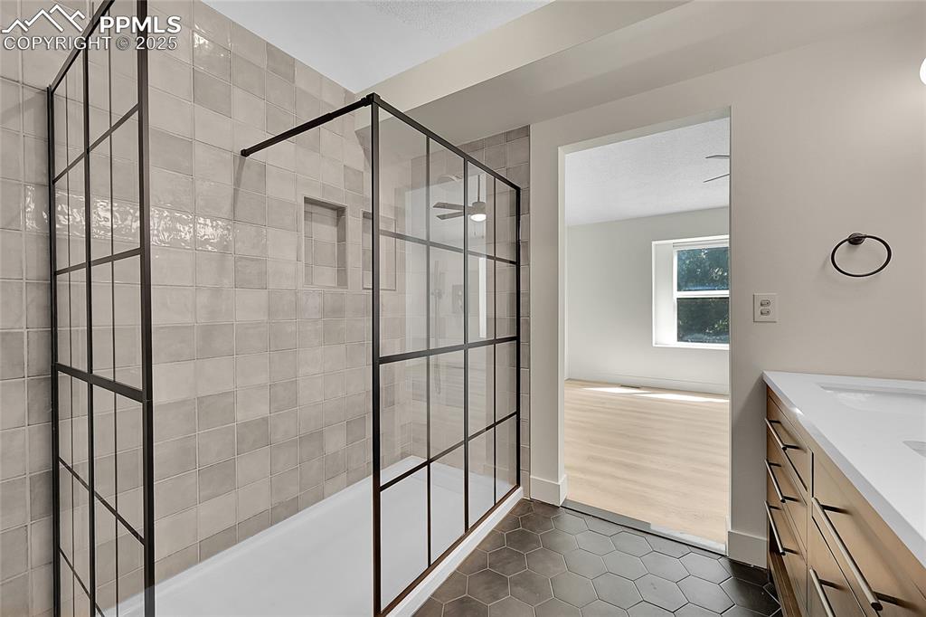 Image 25 of 39: Bathroom featuring dark tile patterned flooring, vanity, and walk in shower