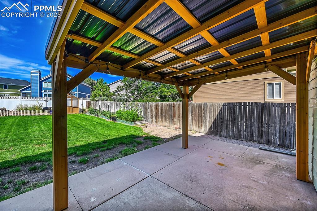 Image 32 of 39: Fenced backyard with a patio area