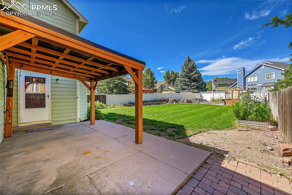 Image 33 of 39: Fenced backyard with a patio area