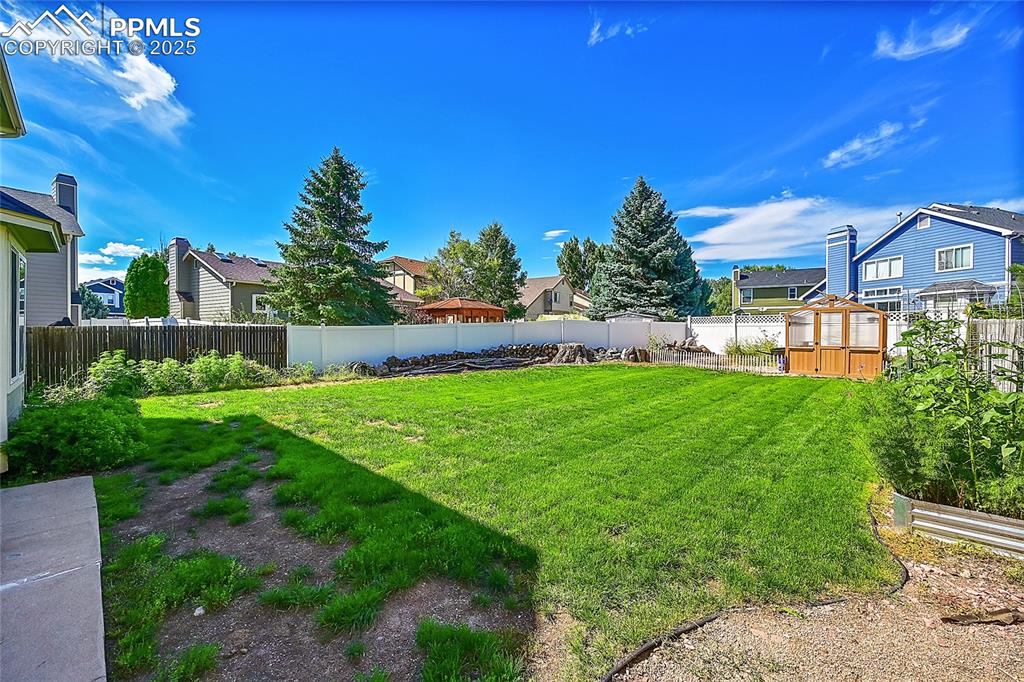 Image 35 of 39: Fenced backyard featuring a residential view and an outdoor structure