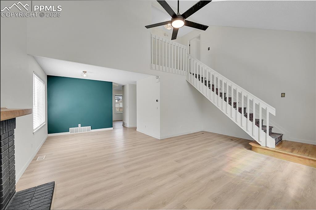 Image 7 of 39: Unfurnished living room with high vaulted ceiling, light wood-type flooring