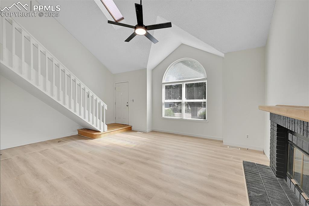 Image 8 of 39: Unfurnished living room with lofted ceiling, light wood finished floors, a 