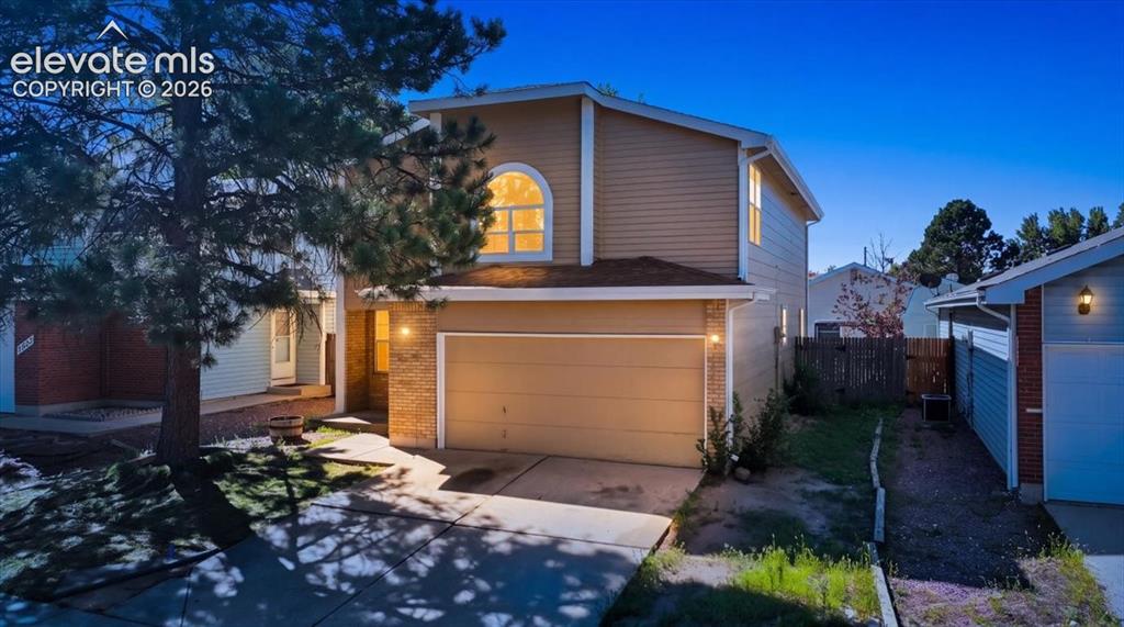 Caption: Twilight curb appeal at , Colorado Springs, CO, with warm exterior lighting on the brick and siding 