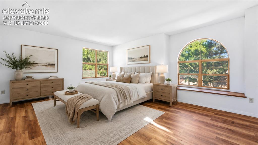 Image 12 of 26: Virtually staged primary suite with an arched window and new LVP flooring a