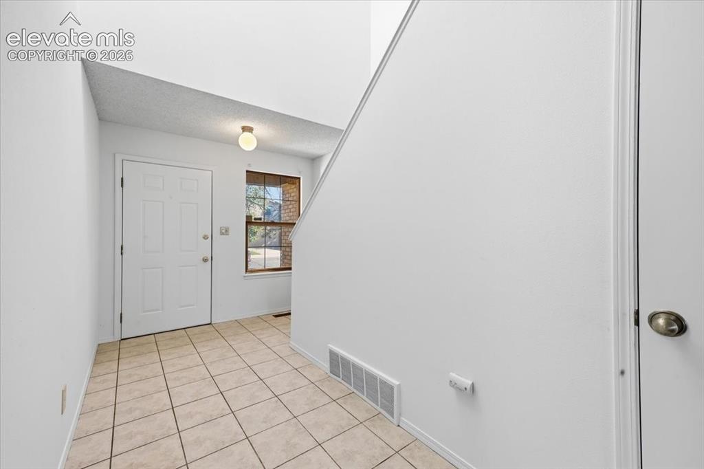 Image 2 of 26: Welcoming tiled entry foyer with staircase at , Colorado Springs, CO.