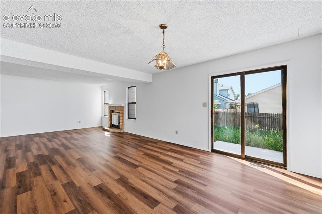 Image 3 of 26: Bright living room with new LVP flooring and a sliding glass door to the ba