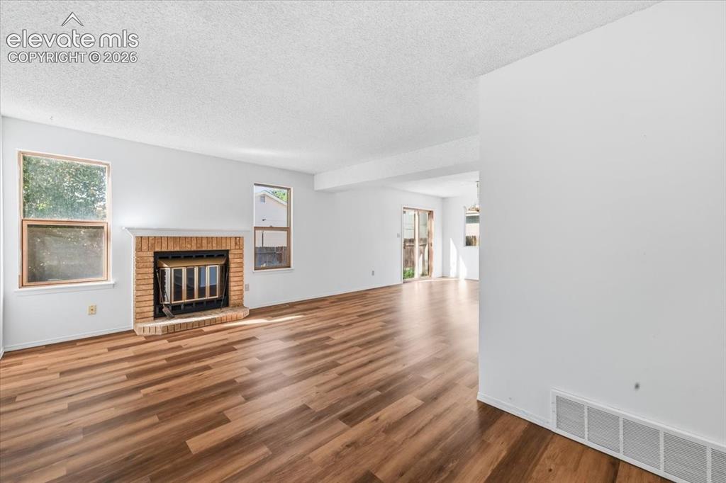 Image 5 of 26: Living room featuring a cozy wood-burning fireplace and new LVP flooring at