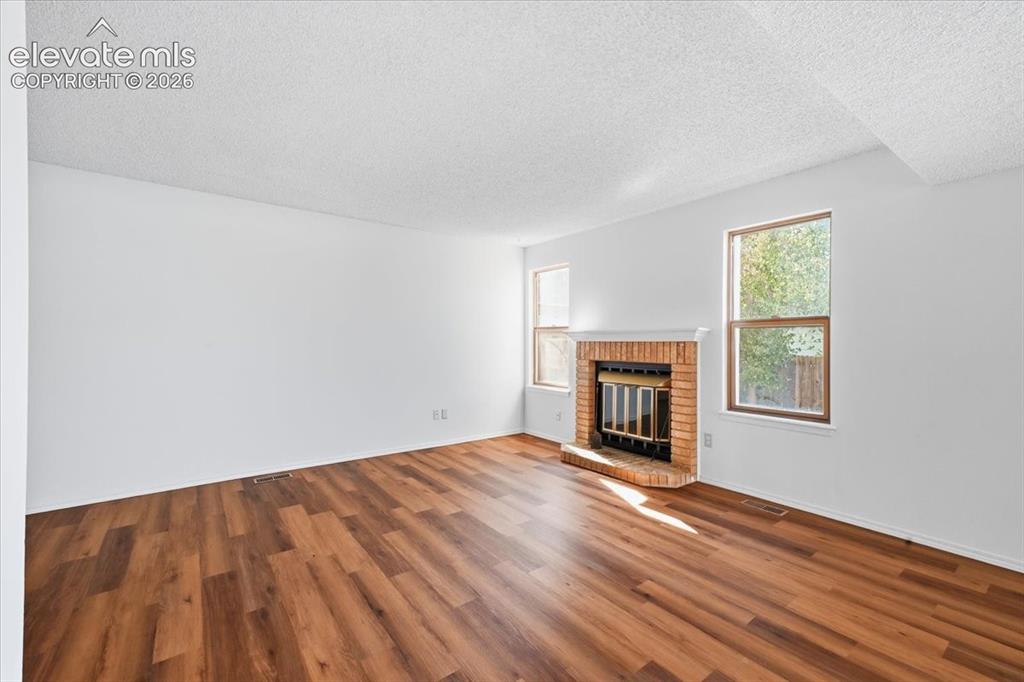 Image 6 of 26: Living room with a wood-burning fireplace and new LVP flooring at , Colorad