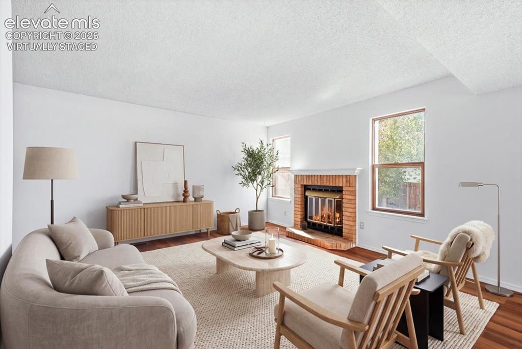 Image 7 of 26: Virtually staged living room with a wood-burning fireplace and new LVP floo