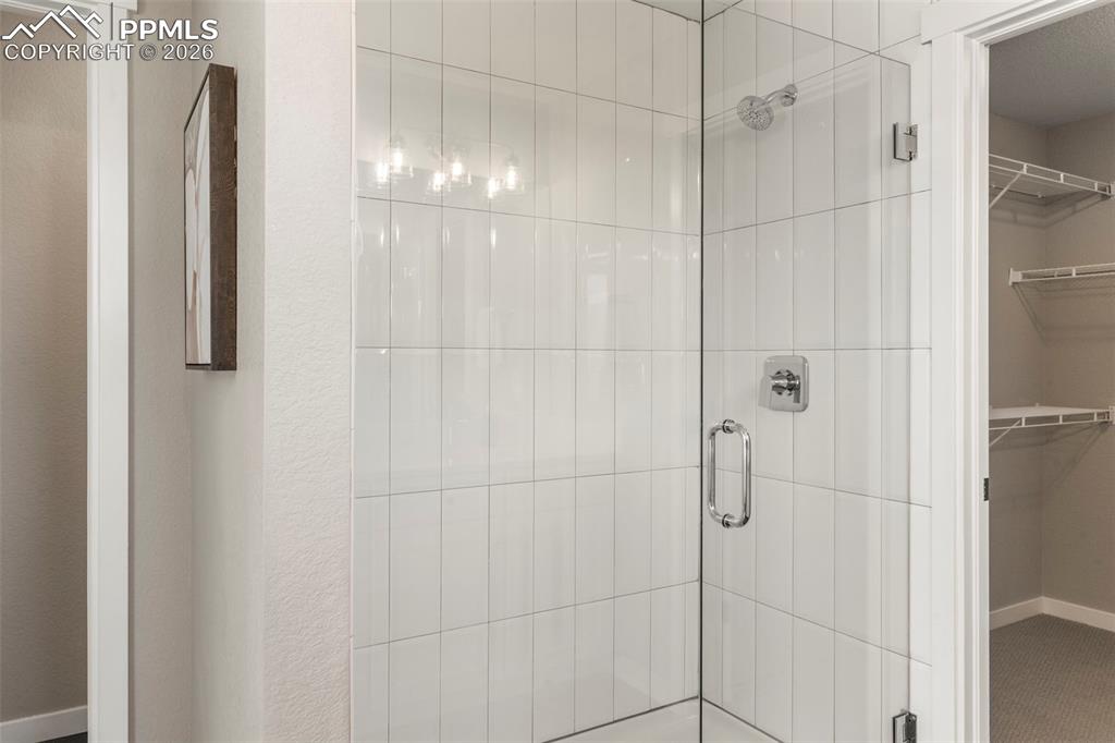 Image 22 of 33: Frameless glass shower with decorative tile in primary suite 