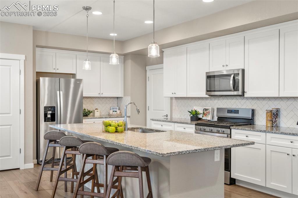 Image 3 of 33: Extra long kitchen island with granite counters, herringbone backsplash, so