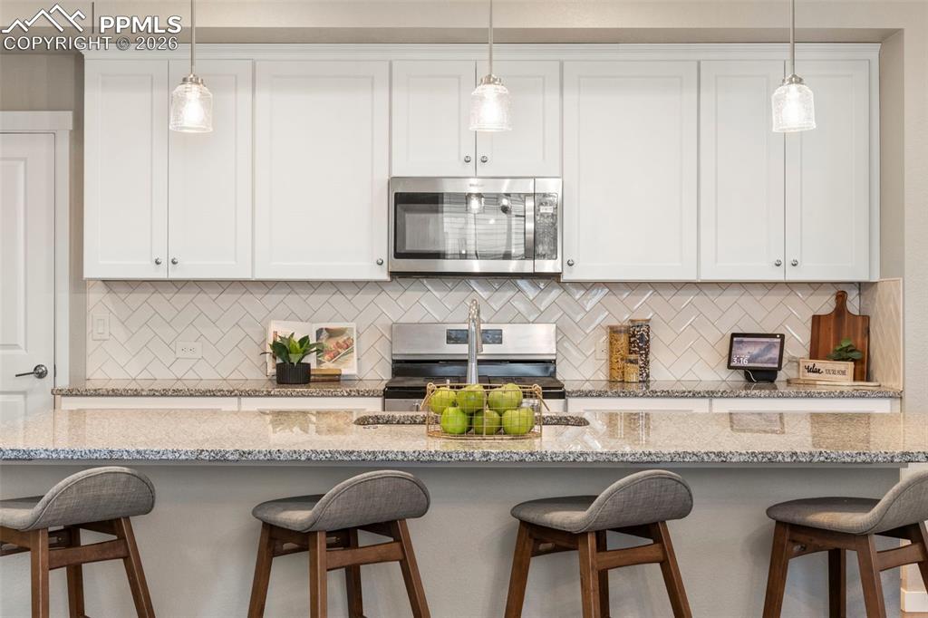 Image 4 of 33: Extra long kitchen island with granite counters, herringbone backsplash, so