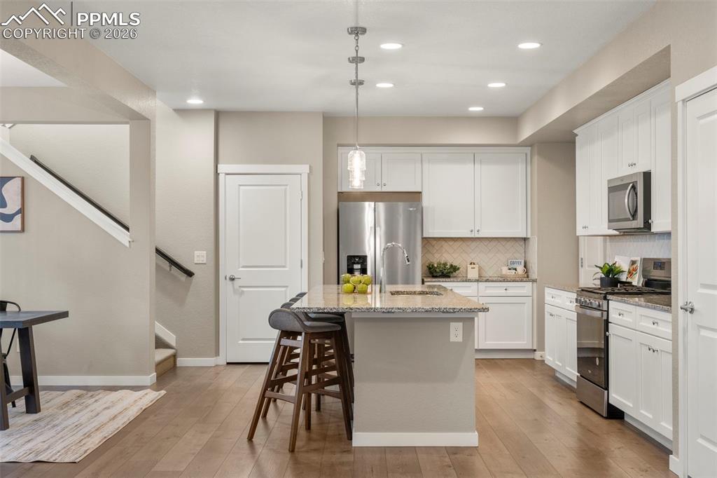 Image 5 of 33: Extra long kitchen island with granite counters, herringbone backsplash, so