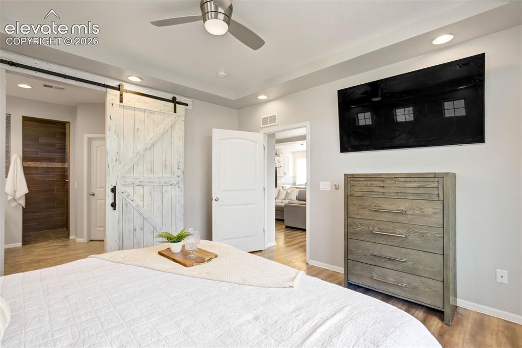Image 17 of 46: Tall ceilings & a barn door leads to the ensuite bathroom.