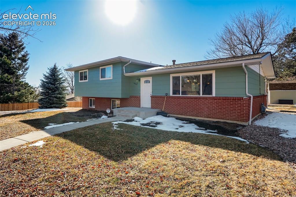 Caption: Split-level residence featuring a brick and siding exterior, front entry door, and a concrete walkwa