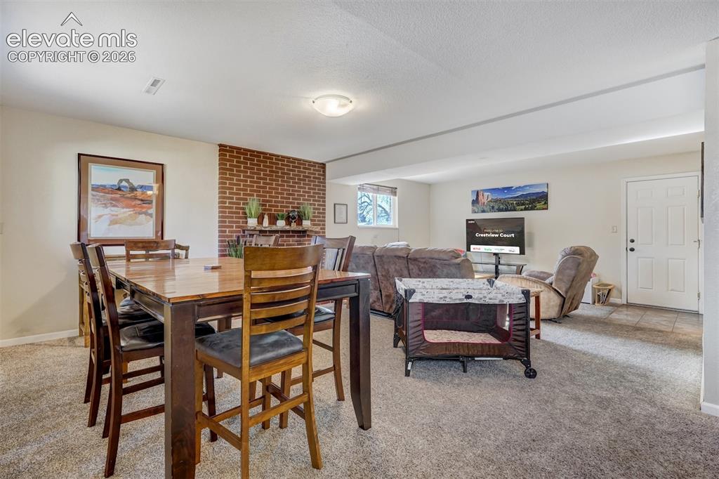 Image 19 of 43: Carpeted living area with a brick accent wall and a window