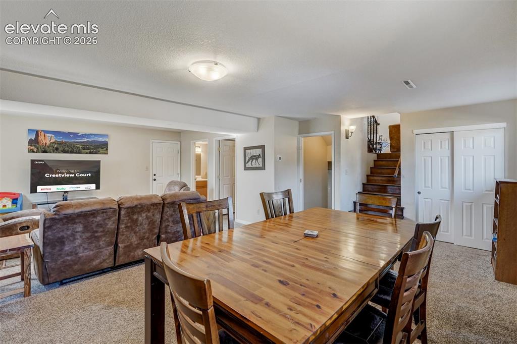 Image 21 of 43: Carpeted living area featuring a wood-finish dining table, recessed lightin