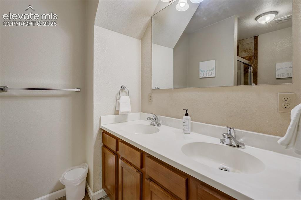 Image 34 of 43: Dual vanity with integrated sinks and chrome fixtures, wood-finish cabinetr