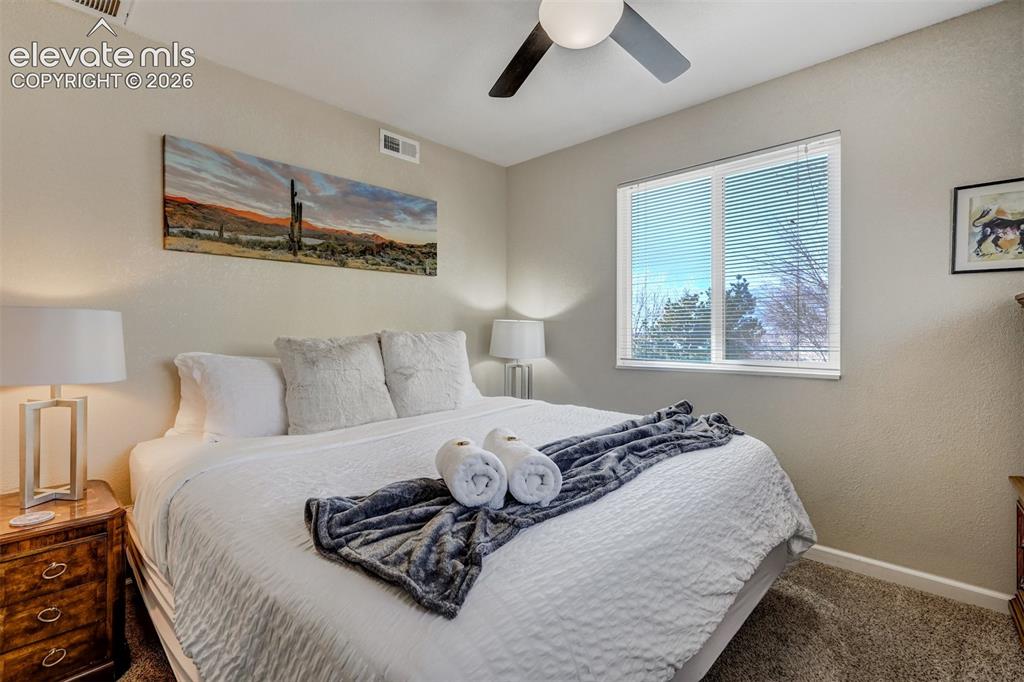 Image 38 of 43: Neutral wall tones complement the window with blinds, ceiling fan, and carp