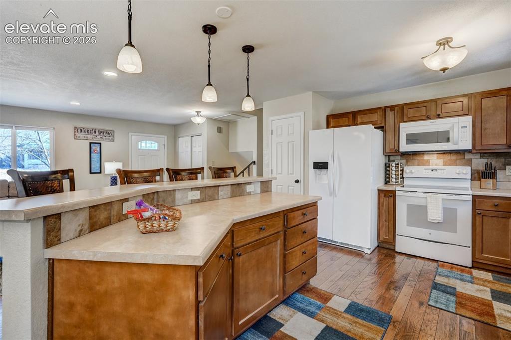 Image 4 of 43: Kitchen featuring wood-finish flooring, wood cabinetry, white appliances, a