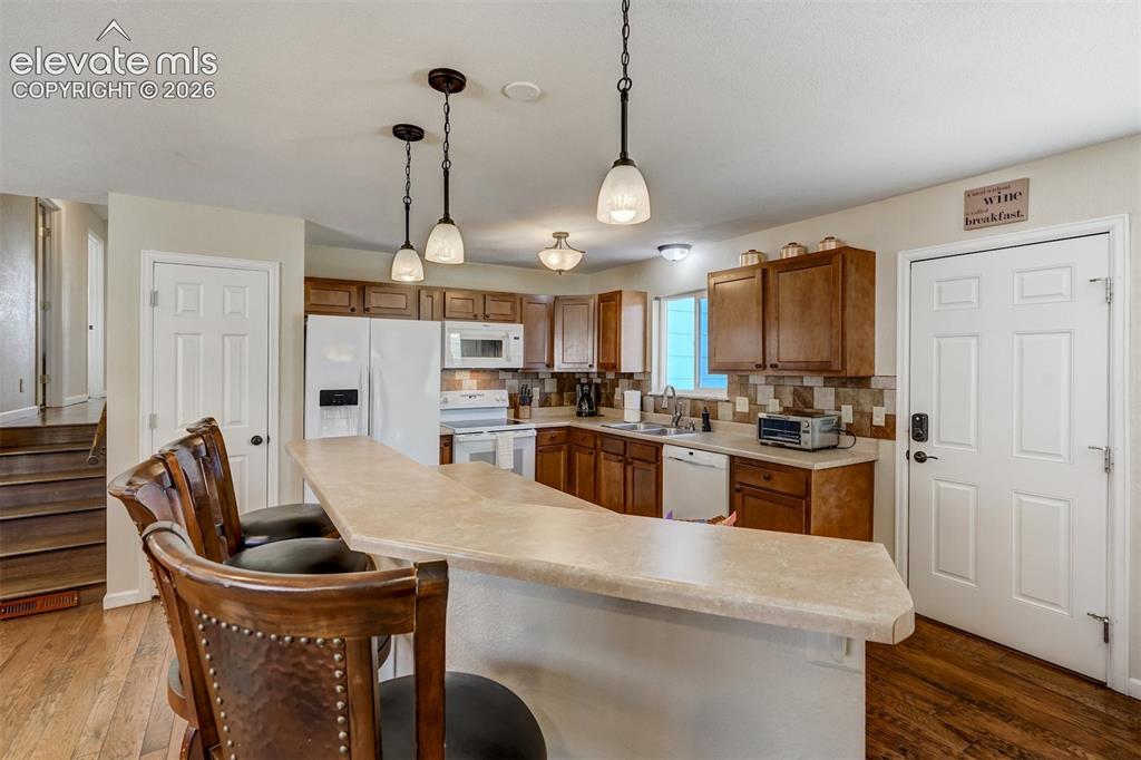 Image 5 of 43: Kitchen featuring wood-finish flooring, a breakfast bar with pendant lighti