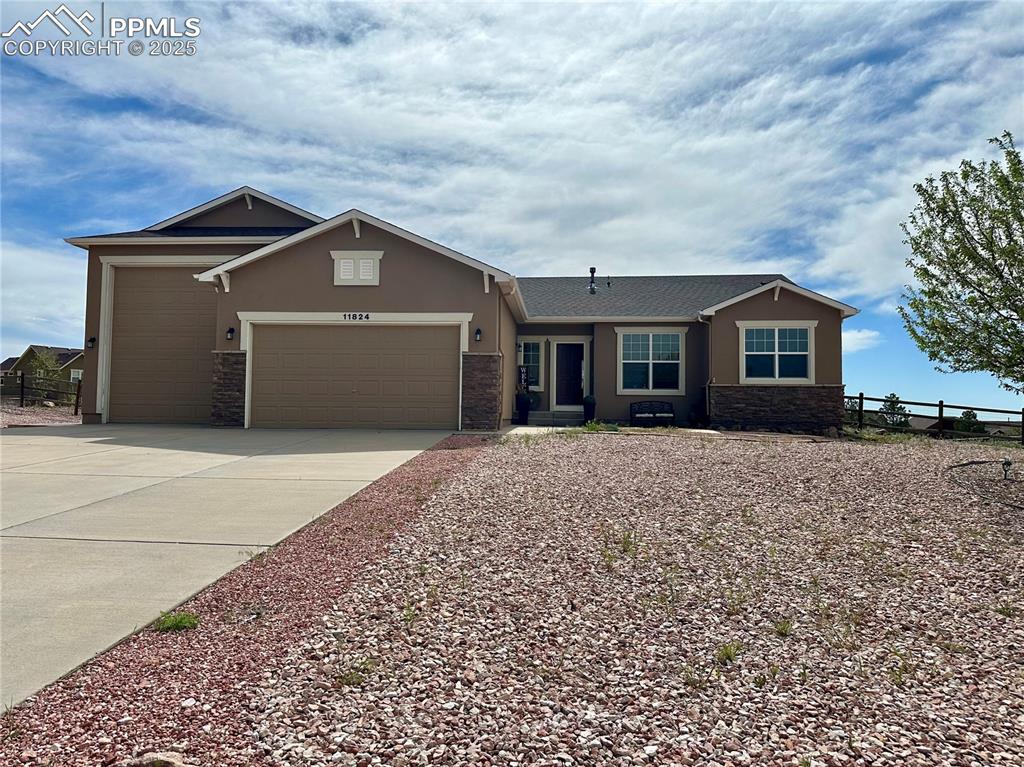 Caption: View of front of property with stone siding, a garage, stucco siding, and driveway