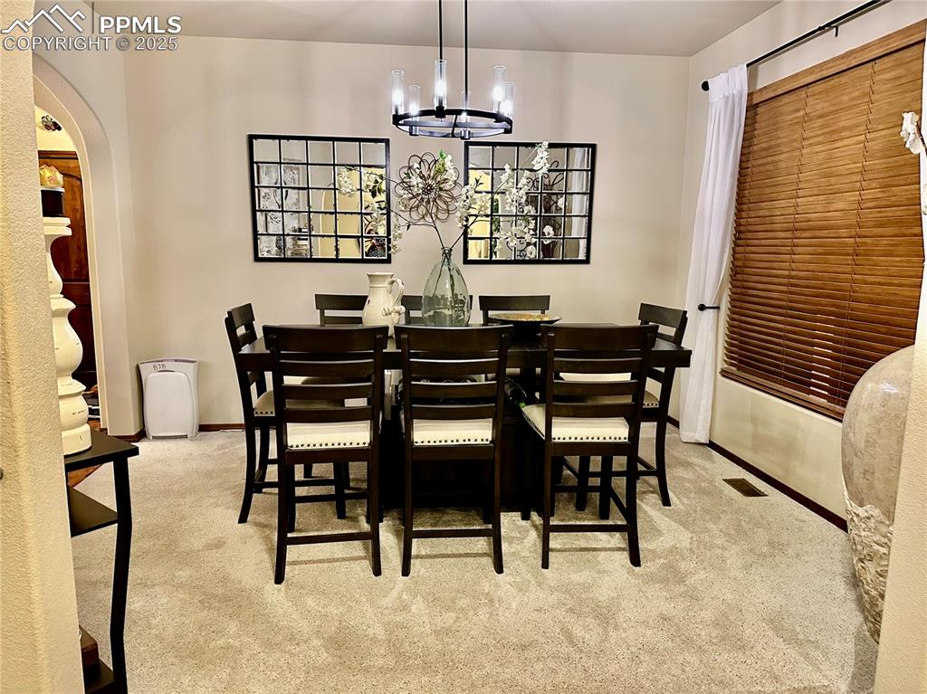 Image 10 of 33: Carpeted dining area with arched walkways and a chandelier