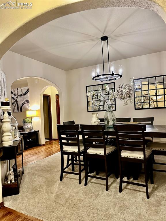 Image 11 of 33: Dining space with arched walkways, wood finished floors, and a chandelier