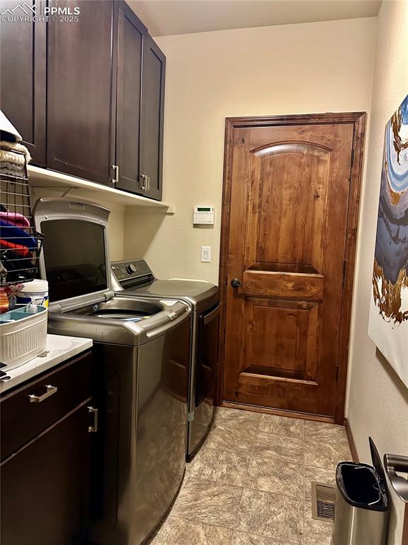 Image 12 of 33: Laundry area featuring cabinet space, washer and clothes dryer, and a textu