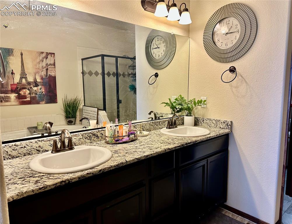 Image 17 of 33: Full bath featuring a textured wall, a stall shower, and double vanity