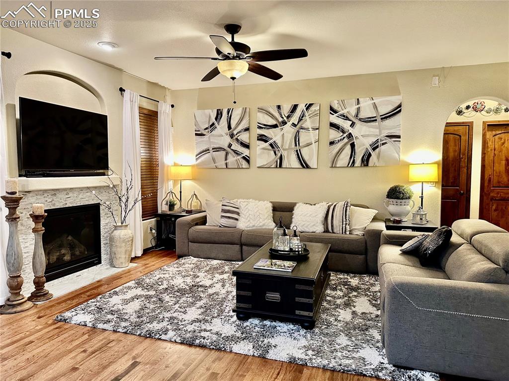 Image 3 of 33: Living room with wood finished floors, ceiling fan, and a fireplace