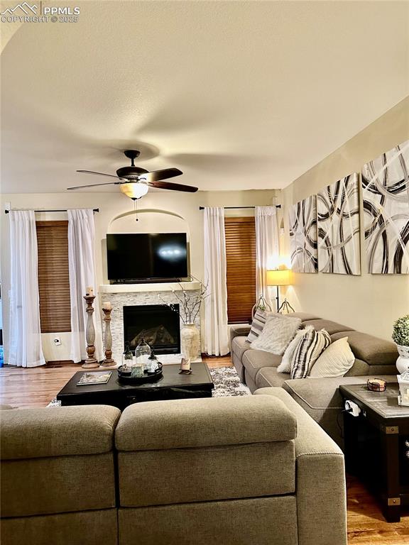 Image 4 of 33: Living room featuring wood finished floors, a fireplace, a ceiling fan, and