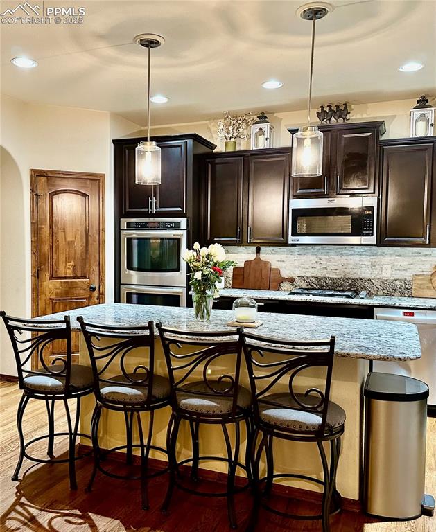 Image 6 of 33: Kitchen with a kitchen bar, light wood finished floors, backsplash, pendant