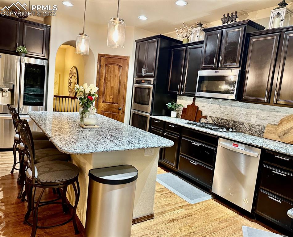 Image 7 of 33: Kitchen featuring tasteful backsplash, stainless steel appliances, a center