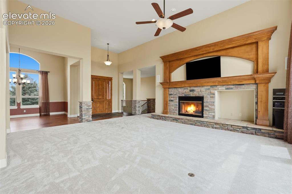 Image 13 of 50: Spacious living area featuring a stone-clad fireplace with a prominent wood