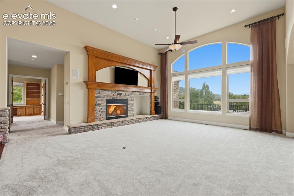 Image 16 of 50: Living area featuring a floor-to-ceiling stone fireplace with a wood mantle